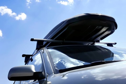 Closeup of a car with a roof rack cargo box traveling under blue sky