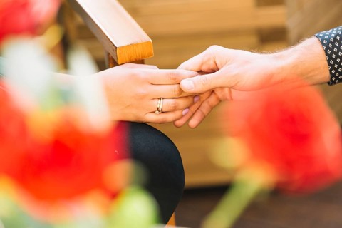 Couple holding hands front blurred rose