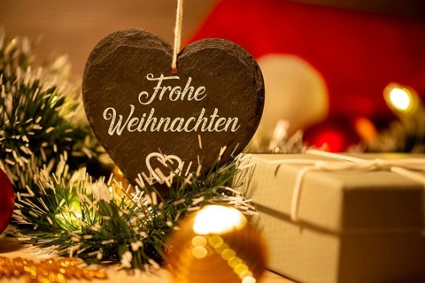 Christmas greetings: Heart with the inscription FROHE WEIHNAHCHTEN in front of Christmas
