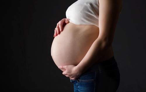 Pregnant woman, expectant mother on black background, close-up of pregnant belly, activity during