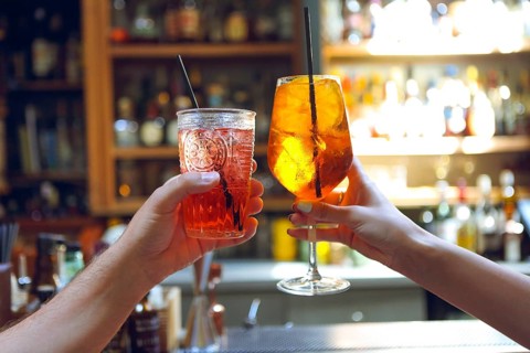 Woman and man raising a glasses of coktails in the bar background