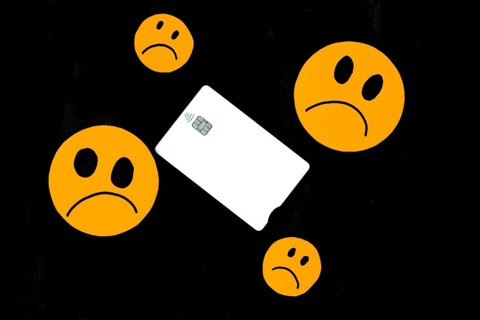 Illustration of orange paper emoticon faces cut out with sad gesture and a white bank card on black