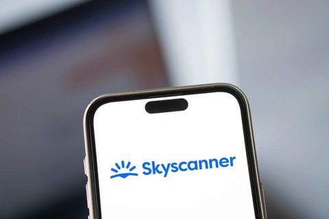 Skyscanner logo is displayed on smartphone. Skyscanner Ltd. is a search aggregator and travel