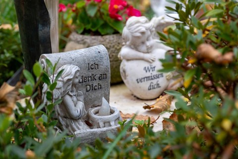 Angel figure on a grave with autumn leaves at the cemetery in Garbsen-Stelingen, Lower Saxony,
