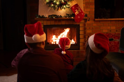 Family wearing Santa Claus hats sitting in front of the fireplace. Poland