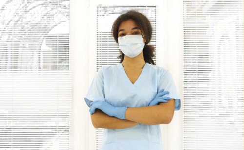 Young tired overworked african american medical worker wearing protective face mask looking to the