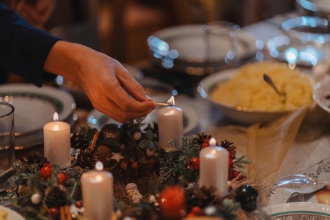 Christmas supper, lighting candles on a table that has been decorated and prepared for the meal. A