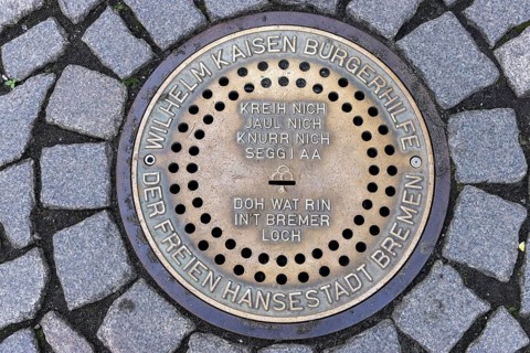 Gully cover Bremer Loch on cobbled market square with singing of Bremen Town Musicians, Old Town
