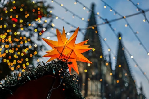 Christmas market at Cologne Cathedral, shining yellow star on a Christmas stall with fairy lights