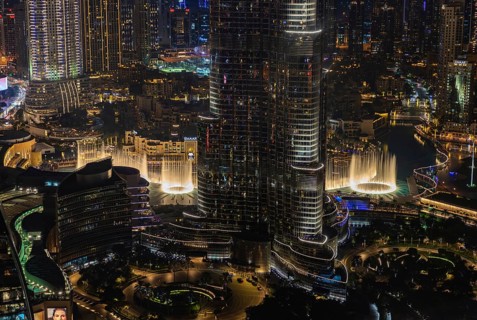 A picture of the Dubai Fountain Show, at night, and the bottom of the Burj Khalifa, next to other