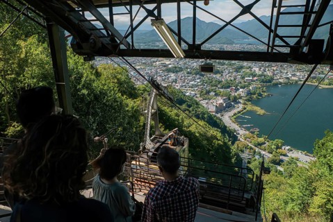 A group of tourists look down on the upcoming cable car from the Mt. Fuji Panoramic Ropeway to the