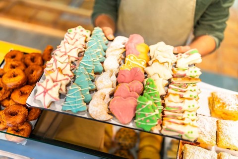 Close-up of a male baker offering a tray with Christmas cookies at shop