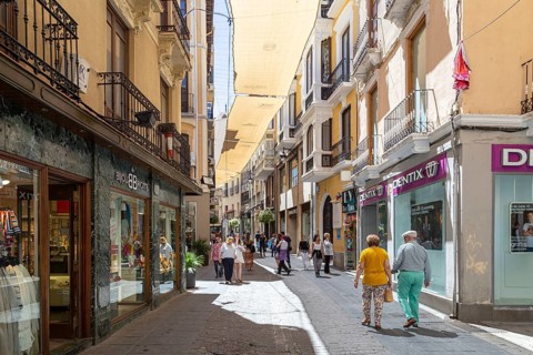 Granada, Spain, May 27, 2019: People walking in a charming narrow shopping street in the historic