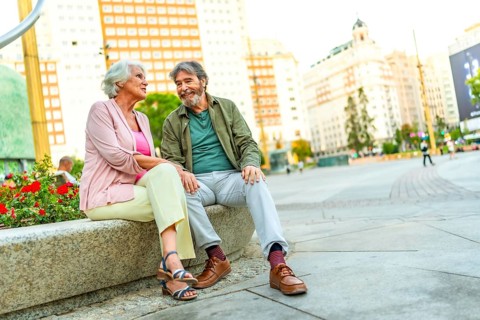 Happy senior couple enjoying a day in the city sitting on urban bench