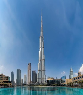 A picture of the Burj Khalifa towering the nearby Downtown Dubai buildings and the blue waters of