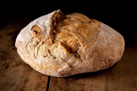 Organic whole wheat round bread on an old wooden table