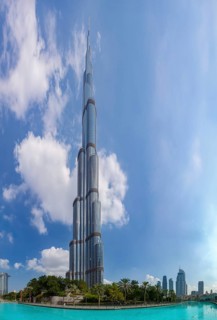 A picture of the Burj Khalifa towering the nearby Downtown Dubai buildings and the blue waters of