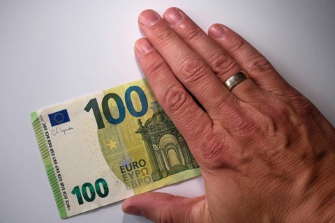 Symbol photo for cash, 100 euro note half covered by a hand, North Rhine-Westphalia, Germany,