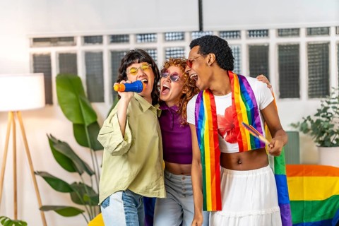 Multi-ethnic and gender diverse lgbt friends singing karaoke during pride party at home