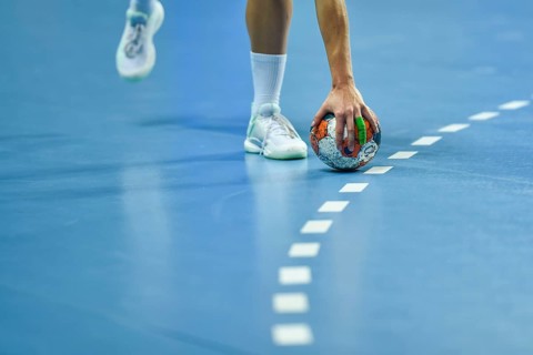 Handball - women's hand taking a ball laying on the 9 meters dotted line.