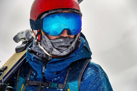 Closeup portrait of ski goggles of a man with reflection of snowy mountains. The mountain range is