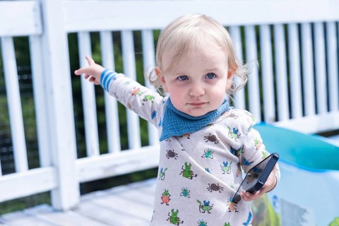 Closeup portrait of a 3 year old boy, with pale white complexion and cute baby grower holding a