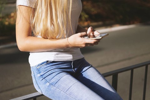 midsection of unrecognizable young woman using her smartphone or mobile phone outside on city