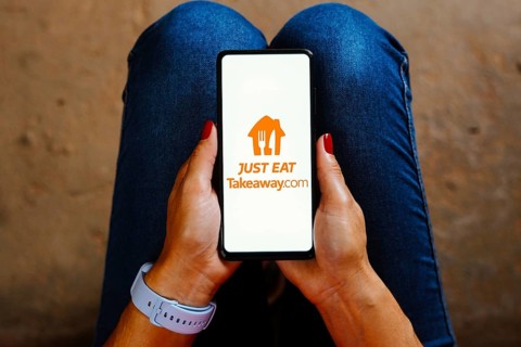 In this photo illustration, the Just Eat Takeaway logo is displayed on a smartphone screen