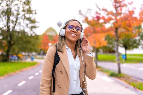 Latin blonde confident businesswoman listening to music walking along the city