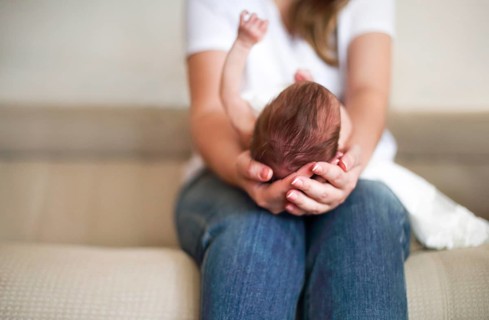 Young mother holding her newborn child. Mom nursing baby. Family at home Close up