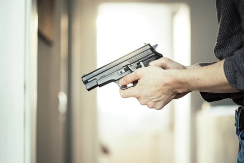 Undercover police agent is holding a black weapon in his hand, ready for shoot