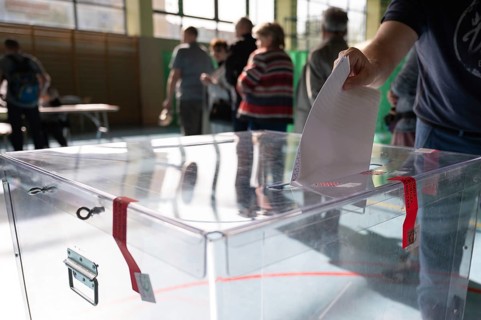 Voter's hand putting the vote into the ballot box. The inscription on the seal in Polish Electoral
