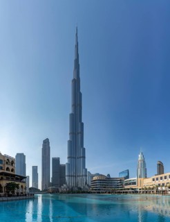 A picture of the Burj Khalifa towering the nearby Downtown Dubai buildings and the blue waters of