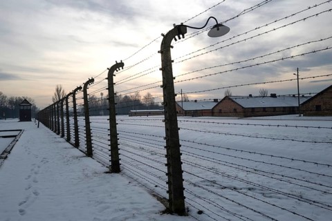 A view of the fence and huts at the entrance to the Auschwitz-Birkenau camp on a snowy day in