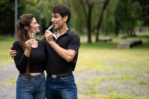Young couple in love eating a popsicle in the park