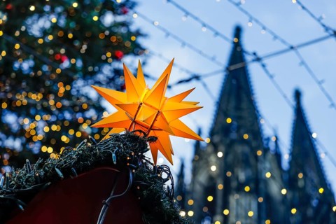Christmas market at Cologne Cathedral, shining yellow star on a Christmas stall with fairy lights