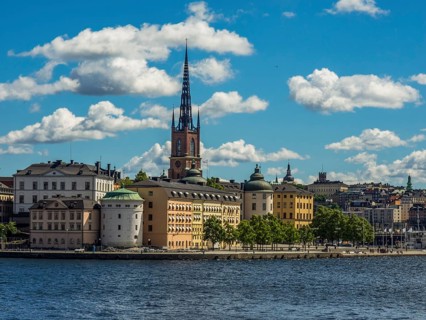 Church tower and historic buildings on the waterfront under a blue sky with clouds, archipelago,