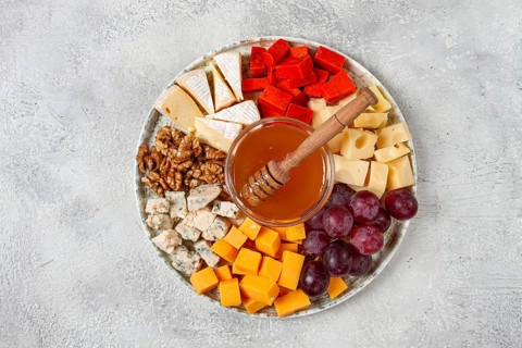 Appetizer, assorted cheese, with nuts and honey, on a round plate, top view, no people