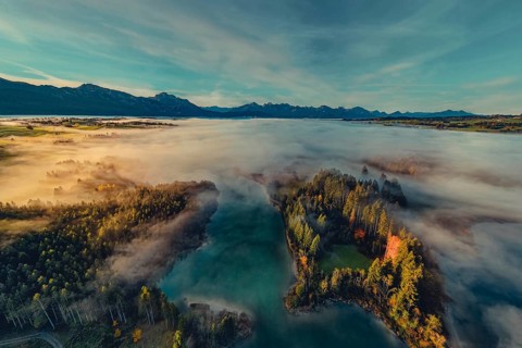 Autumn sunrise in the foothills of the Alps with fog at Illasbergsee and Forggensee near Halblech
