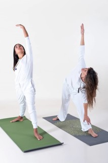 Two women dressed in white doing yoga over white background. Utthita trikonasana yoga pose. Studio