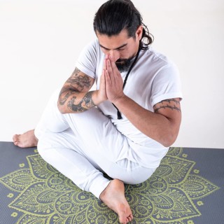 A man dressed in white doing yoga on a mat over white background. High angle view