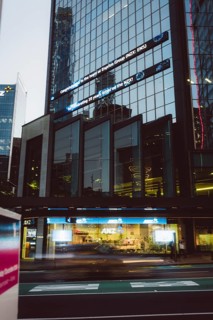 Street scene at night with illuminated shop windows and a reflective glass façade, new zealand