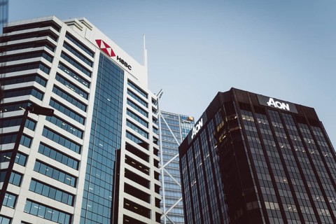 Two modern office buildings with the logos of HSBC, PWC and AON under a clear sky, Auckland, New