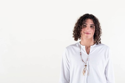 Portrait of a young man dressed in white yoga clothes over white background while looking at camera