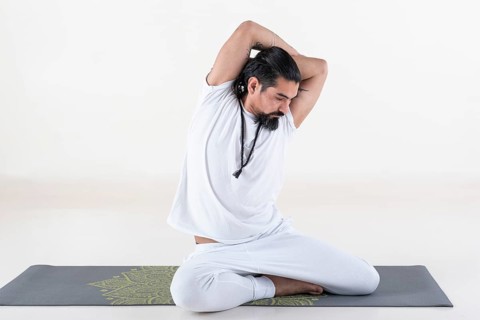 A man dressed in white doing yoga on a mat over white background. bharadvajasana yoga pose. Studio