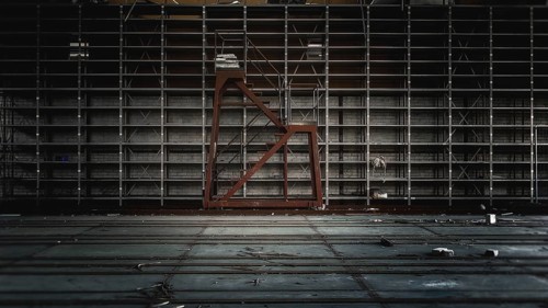 Empty warehouse with large metal shelves in gloomy light, Gerresheimer Germany, Lost Place,