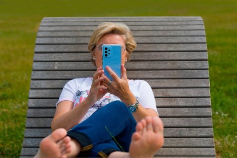 Woman on a wooden couch holding her mobile phone