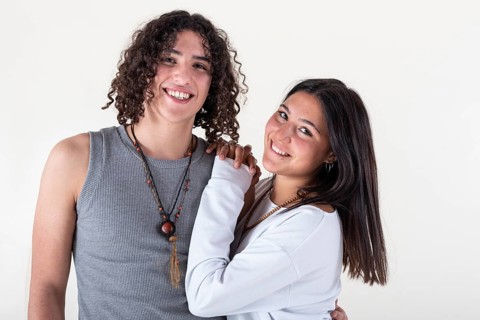 Portrait of a young couple dressed in yoga clothes looking ti the camera white background. Studio