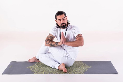 A man dressed in white doing yoga on a mat over white background. Front view