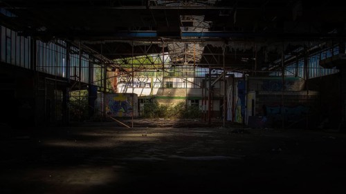 Dark abandoned factory building with light beam and graffiti, Gerresheimer Germany, Lost Place,